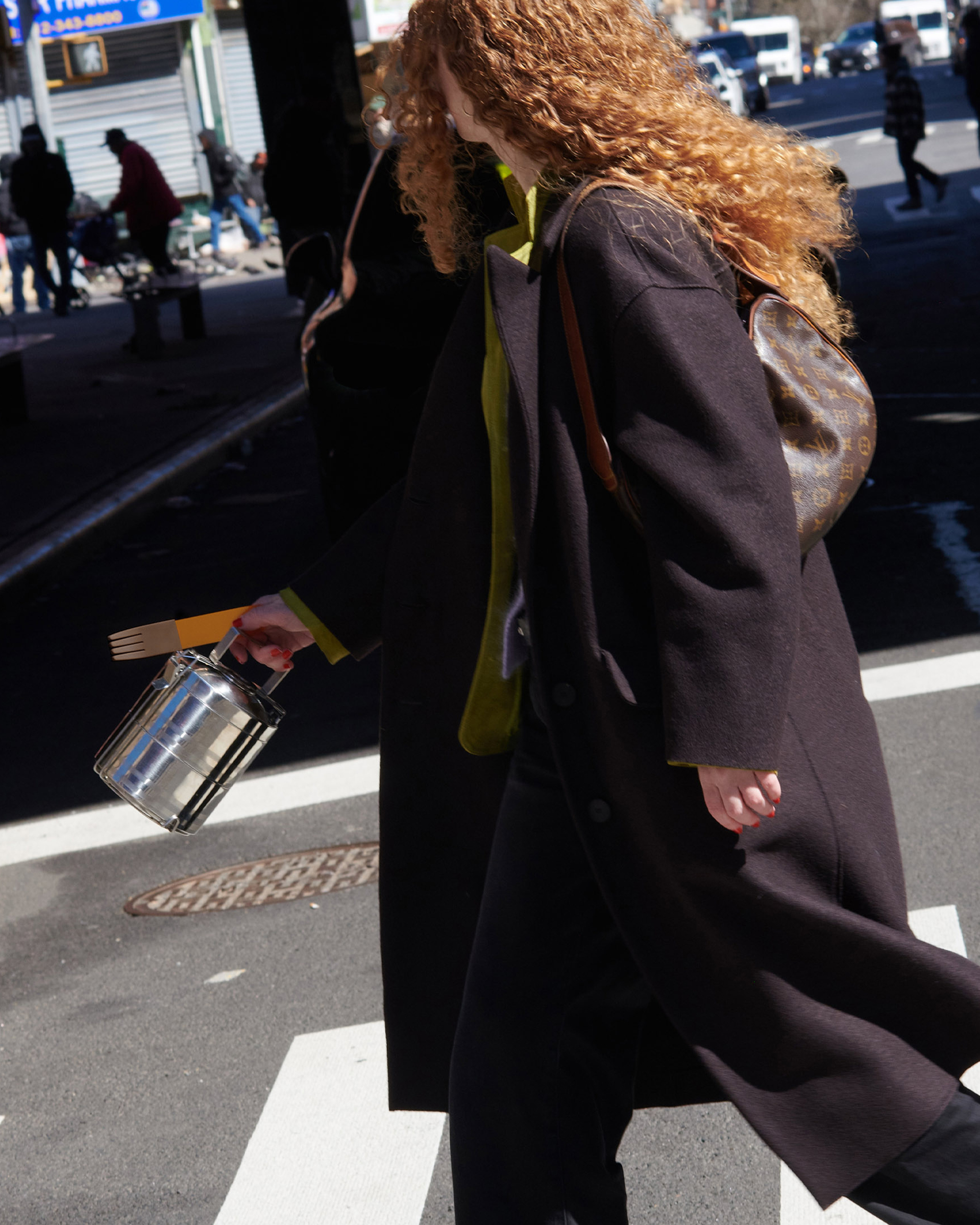 Girl walking down the street carrying a stainless steel lunch tin and orange fork
